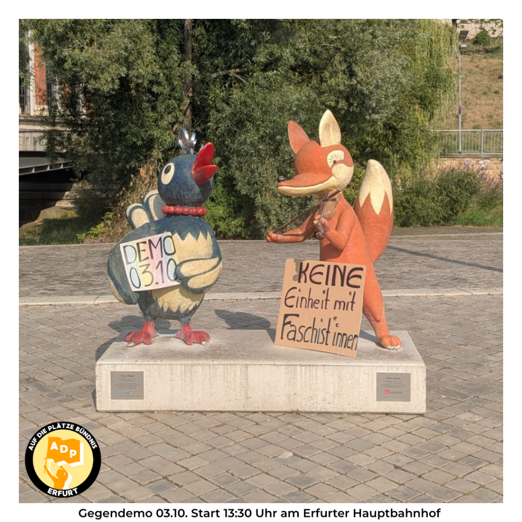 Die Kika-Figuren Herr Fuchs und Frau Elster werben für die Demo gegen die AfD am 3. Oktober. Sie halten Schilder mit "Demo 3.10." und "Keine Einheit mit Faschist*innen"